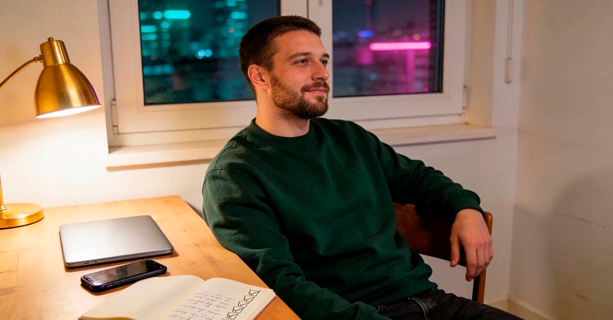 dating app profile reset 2026 — late 20s black man sitting on a sofa at night editing his dating profile photos and bio on his phone