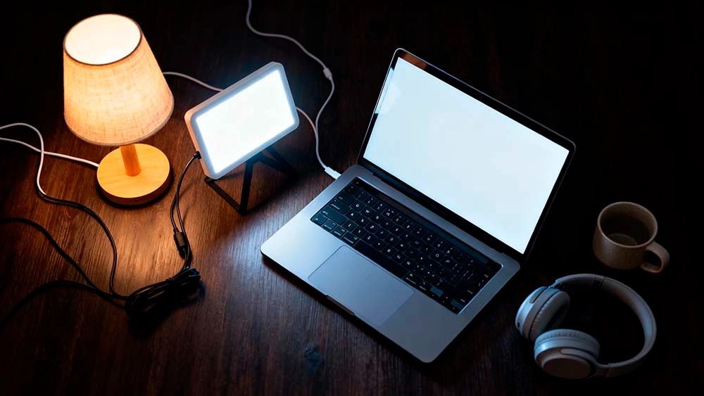 winter video date lighting for men — minimal desk setup with laptop, small led panel and warm desk lamp creating soft light for a video call